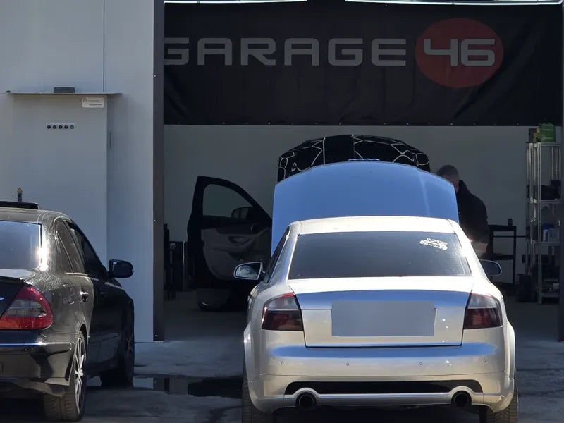 Входът на монтажния център Garage46 в Бургас с банер GARAGE46 и автомобил с отворен капак